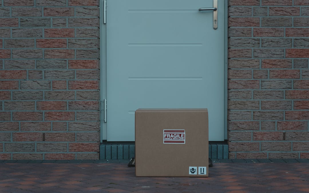 Cardboard package placed at the brick entrance of a residential door, timestamped photo evidence